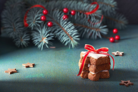 Stack of Christmas star cookies tied up pith red ribbon on green and red festive background with...