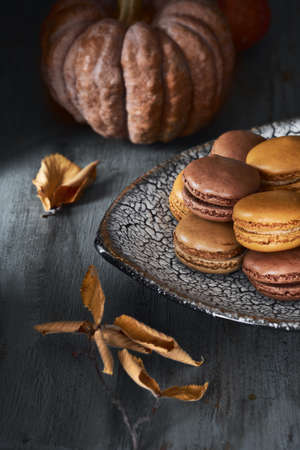 Autumn macarons with caramel and cocoa with coffee on dark rustic wooden backgroundの写真素材