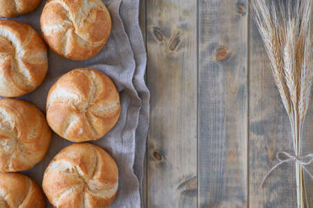 Crusty round bread rolls, known as Kaiser or Vienna rolls on linen towel on rustic wood, flat lay with copy-spaceの写真素材