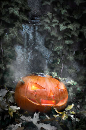Halloween pumpkin outdoors with candle inside and ivy leaves aroundの写真素材