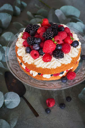 Fresh delicious homemade cake with whipped cream and berries on dark green tableの写真素材