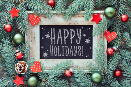 Christmas frame in green and red, top view with text "Happy holidays". Fir twig decorated with baubles, hearts and starsの写真素材