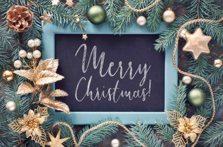 Green and golden Christmas background. Decorated fir twigs around chalk board on dark background. Top view with text "Merry Chtistmas!".の写真素材