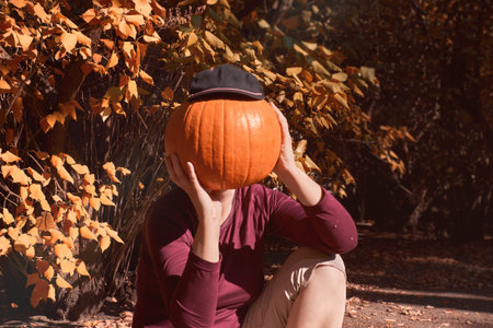 Halloween girl with pumpkin head oudoors in Autumn gardenの写真素材