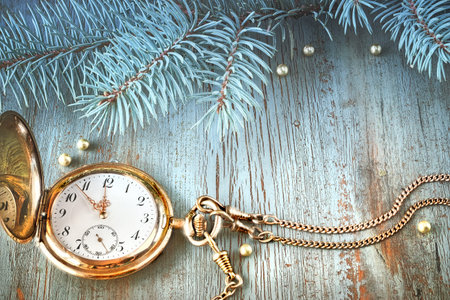 Vintage pocket watch showing five to twelve on gray rustic background with Christmas twigs and...