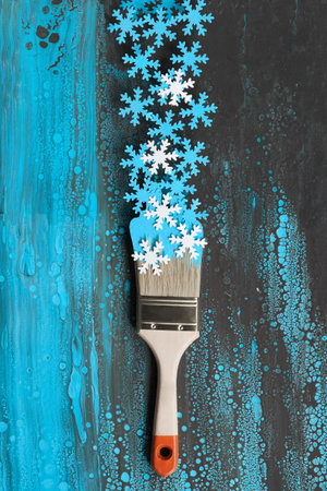 Concept top view flat lay background in blue and white with painting brush loaded with paper snowflakesの写真素材