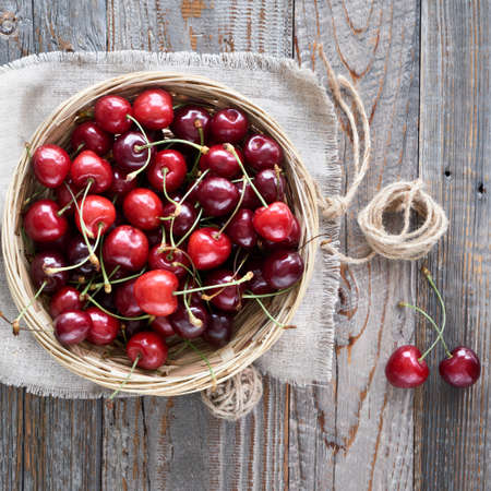 Tasty cherry, flat lay on rustic wooden table with linen towel, square compositionの写真素材