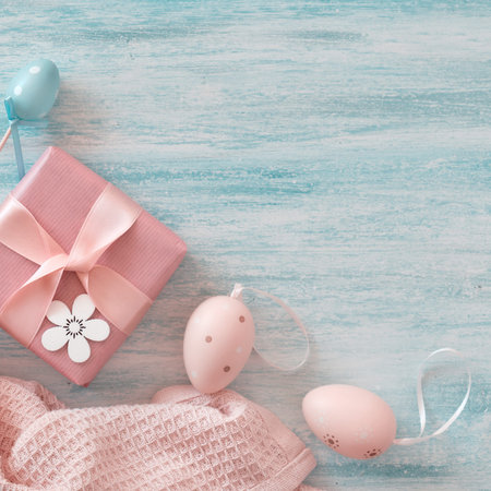 Easter flat lay in pastel colors with copy-space. Wrapped gift box, decorative flowers and Easter...