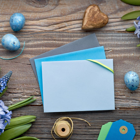 Top view of paper cards with copy-space, blue hyacinth flowers and Easter eggs on rustic wooden...