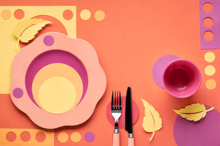 Autumn concept flat lay in bold colors with plate, fork, knife and decorative Autumn leaves in yellow, orange, red and purple colors. Seasonal menu concept.の写真素材
