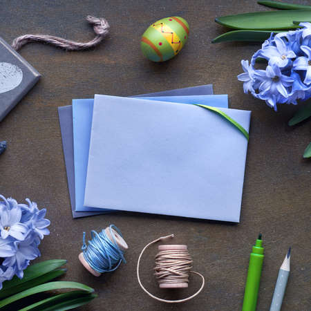 Top view of paper cards with copy-space, blue hyacinth flowers and Easter eggs on dark texured background, square compositionの写真素材