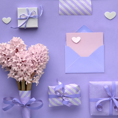 Purple springtime  background with pink hyacinth flowers, wrapped gift boxes and decorative hearts, copy-space on empty card in envelope, square compositionの写真素材