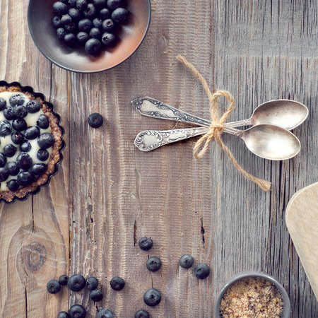 Top view on wholegrain blueberry tarts with vanilla cream on rustic wooden backgroundの写真素材