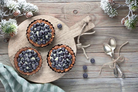 Winter blueberry tarts, flat lay on rustic wooden table decorated with pine twigsの写真素材