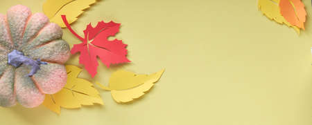 Panoramic Autumn composition with decorative pumpkin and paper leaves, flat lay on yellow paper background with copy-space.の写真素材