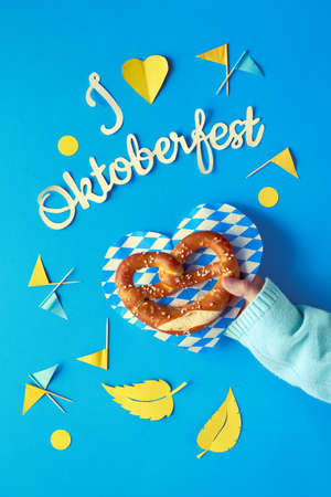 Paper text "I love Oktoberfest", flat lay on paper background with pretzel on paper plate, decorative hearts, flags and Autumn leaves.の写真素材