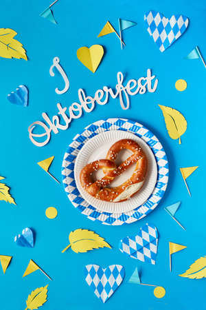 Paper text "I love Oktoberfest" in German, flat lay on paper background with pretzel on paper plate, decorative hearts, flags and Autumn leaves.の写真素材