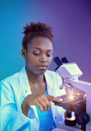 African scientist or graduate student in lab coat working with modern light microscope. Futuristic...