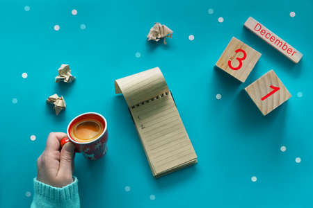 Christmas do list with pen, craft paper notebook, wooden calendar and coffee on blue pastel table top view. Flat lay style, blue paper background with snowflakes. Holiday planning conceptの写真素材