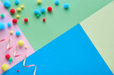 Top view on colorful fluffy balls, flat lay on pastel colored geometric paper background with copy-spaceの写真素材