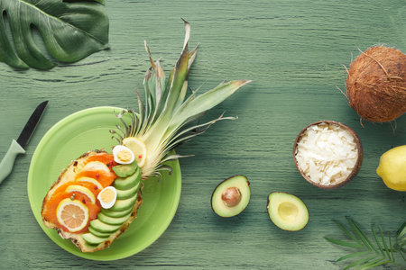 Top view on pinapple boats with smoked salmon and avocado slices with lemon and quail eggs, flat lay...