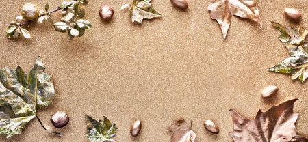 Autumn flat lay with painted golden leaves and copy-space on sparkling golden paper. Top view,...