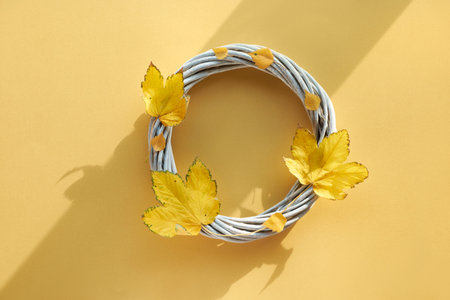 Yellow paper flat lay with decorative wattle wreath decorated with natural yellow Autumn maple...