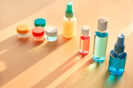 Various toiletries in clear plastic travelling bottles on neutral paper background with long shadows, copy-spaceの写真素材