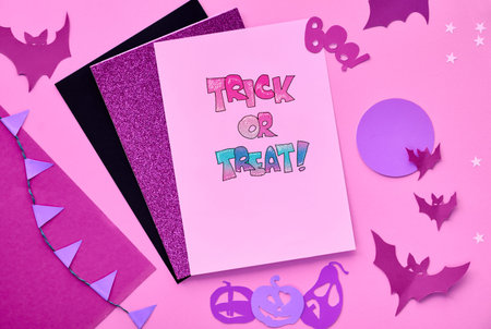 Creative paper craft Halloween flat lay in pink, light purple and black. Top view with copy-space on...
