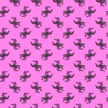 Halloween decorations concept - seamless pattern with black plastic spiders on glowing pink backgroundの写真素材