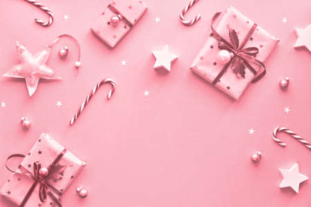 Festive monochrome pink Christmas background with pink gift boxes, stripy candy canes, trinkets and decorative stars, geometric creative flat lay with copy-spaceの写真素材