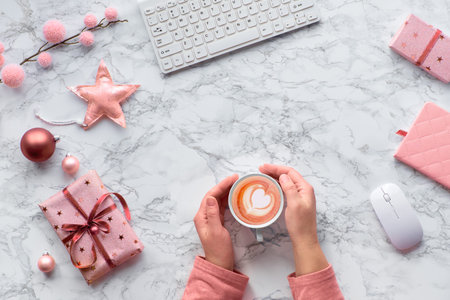 Hands warming up from warm cup of cafe latte with heart shape