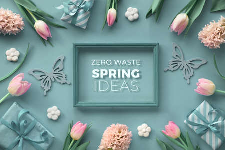 Text "Zero Waste Spring ideas" in wooden frame. Creative springtime flat lay, top view on blue paper with border from pink tulips, hyacinth and spring decorations without plasticの写真素材