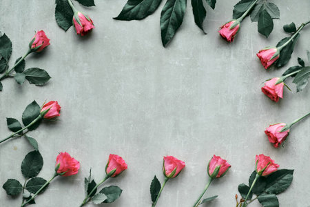 Floral frame made of natural fragrant pink roses, flat lay, top view on light stone background with...