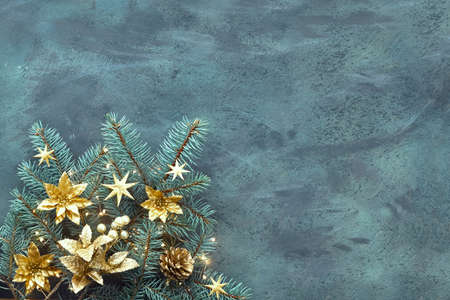 Christmas or New Year flat lay background on textured board with text space. Fir twigs decorated with golden trinkets, flowers and Xmas lights on dark textured background with copy space.の写真素材