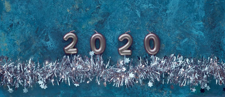 Candle numbers 2020 and shiny sparkling Xmas garland with lights and tiny stars on dark blue grunge...