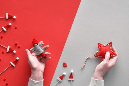 Christmas flat lay with female hands holding textile star and decorative doll on diagonal geometric...