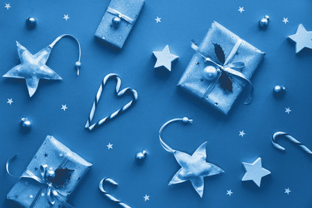 Festive monochrome blue color Christmas background with gift boxes, stripy candy canes, trinkets and...