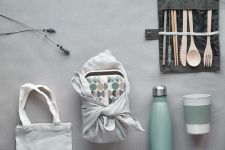 Creative top view, zero waste packed lunch kit, takeaway lunch box set on cotton bag, organizer of bamboo cutlery, bamboo lunch box and reusable cup. Sustainable lifestyle, flat layout on craft paper.の写真素材