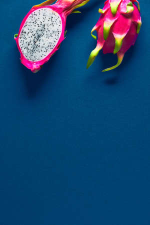 Creative flat layout with fresh organic dragonfruit (pitaya or pitahaya) on trendy classic blue paper background with copy-space, place for your textの写真素材