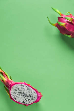 Creative flat layout with fresh organic pink, white and green dragonfruit (pitaya or pitahaya) on vibrant green mint paper background. Trendy top view, copy-space. Flat lay of the fruit cut in half.の写真素材
