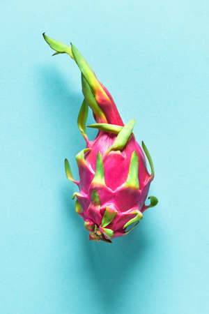 Creative flat layout with fresh organic pink, white and green dragonfruit (pitaya or pitahaya) on blue mint paper background. Trendy top view, flat lay of the whole fresh ripe fruit ready to eat.の写真素材