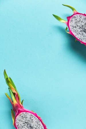 Fresh dragonfruit, pitaya or pitahaya, cut in half on blue mint background. Creative flat layout with copy-space, place for your text. Trendy exotic fruit in vibrant bold pink and green colors.の写真素材