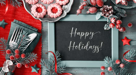 Flat lay with Xmas decorations in green and orange with frosted berries and trinkets. Coffee and jam Christmas cookies, text "Happy Holidays", panoramic image.の写真素材