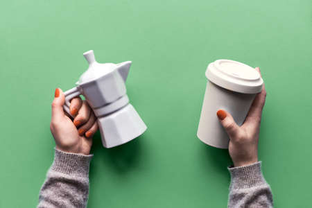 Reusable coffee mug or keep cup and white ceramic coffee maker in woman's hands on neo mint light green background. Creative flat lay, top view image. Trendy zero waste concept with reusable cups.の写真素材