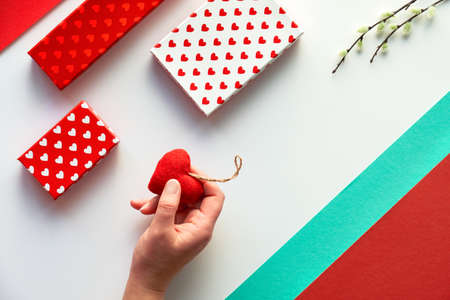 Valentine day flat lay, top view in red, white and green mint colors. Geometric two tone split paper background with gift boxes, felt heart and pussy willow flowers. Happy Valentine's day!の写真素材