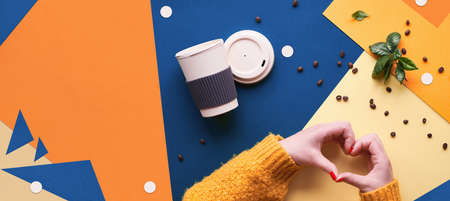 Zero waste coffee concept. Eco friendly reusable coffee cups in hands. Panoramic geometric flat lay on split paper. Creative background in classic blue, orange and yellow colors.の写真素材