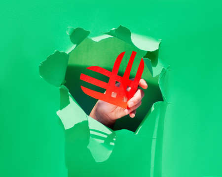 Creative paper lay, top view on the concept of Giving Tuesday or Givingtuesday. Paper craft, long shadows. Paper stripe heart in hand trough a ragged hole torn in trendy neo mint color paper.のeditorial素材
