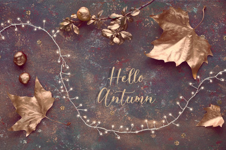 Autumn, creative panoramic flat lay. Top view of painted golden leaves, festive light garland on...
