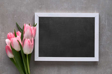 Greeting text "Happy Mother's day!" on blackboard with white tulips with pink stripes, flat lay on grey stone backgroundの写真素材